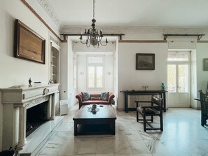 Un salon spacieux avec une cheminée, un lustre, un canapé et une table basse.