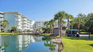A resort with a clear pond, white buildings, and palm trees. - Seaside Inn Condo, Screen Porch, Quiet Setting, Pool Plaza, Resort Beach Access (Pawleys Island)