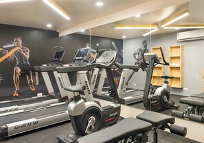 A gym with treadmills, a stationary bike, and weight benches. - Bloom Hotel - Jubilee Hills (Hyderabad)
