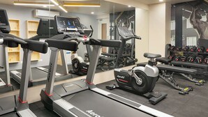 Un gimnasio con cintas de correr, una bicicleta estática y equipo de levantamiento de pesas.