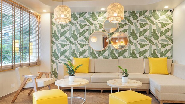 Una sala de estar moderna con un sofá, sillones amarillos y mesas redondas.