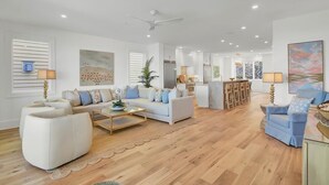 A spacious living area with a sofa set, a coffee table, and a dining area with chairs. - New Construction 5BR | Designer Coastal Home in Wild Dunes (Isle of Palms)