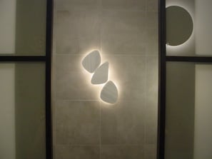 Un mur agrémenté d’un luminaire aux formes géométriques et d’un élément décoratif circulaire.