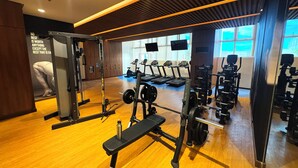 Une salle de sport équipée de matériel d’exercice, dotée de planchers en bois et de grandes fenêtres.