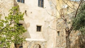 Une cour intérieure avec un bâtiment en pierre doté de deux fenêtres et d’une arche.