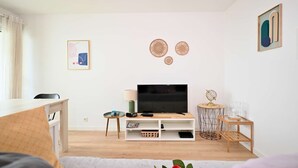 Een moderne woonkamer met een flatscreen televisie, een salontafel, een boekenkast en decoratieve muurkunst.