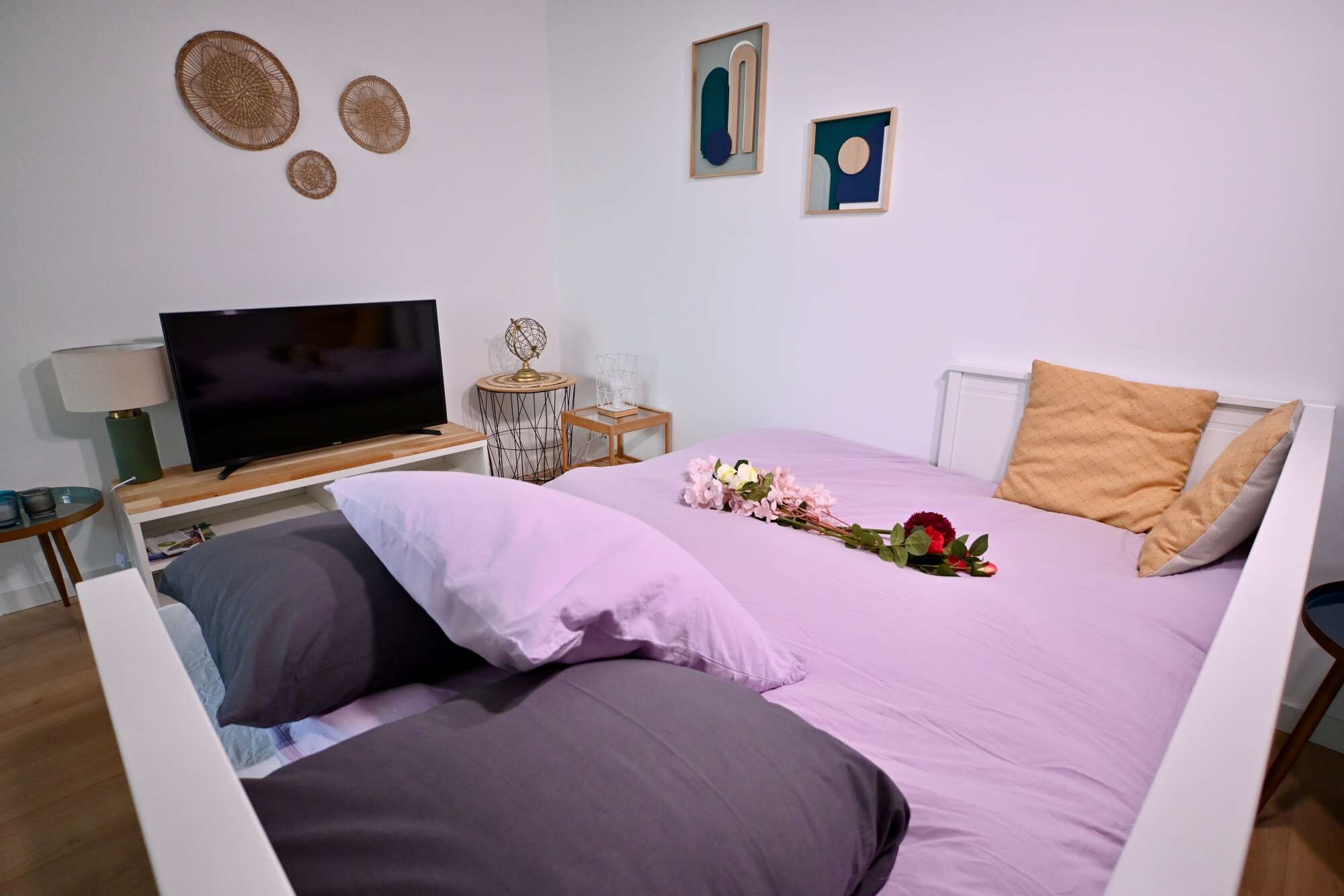 Quarto bem arrumado com cama, televisão, abajur e arte decorativa na parede.