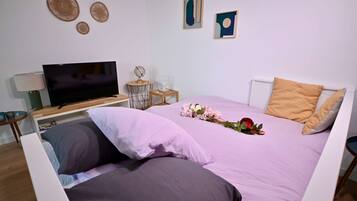 Quarto bem arrumado com cama, televisão, abajur e arte decorativa na parede.