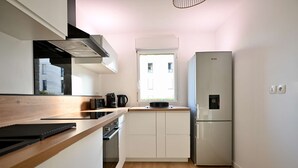 Een compacte keuken met een inbouwoven, een koelkast en een raam dat natuurlijk licht binnenlaat.
