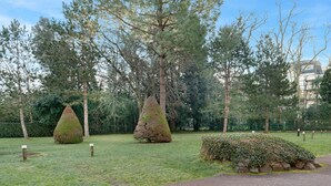 A park with a paved path, neatly trimmed hedges, and conical tree sculptures. - Flat for 2 adults and 1 child - View of the Port (La Baule-Escoublac)