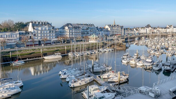A marina with numerous boats docked, a bridge, and buildings in the background. - Flat for 2 adults and 1 child - View of the Port (La Baule-Escoublac)