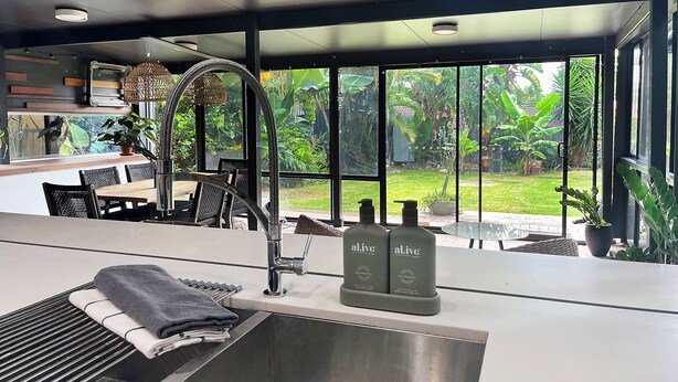 Una cocina moderna con un ventanal amplio, un comedor y vistas a un jardín exuberante.