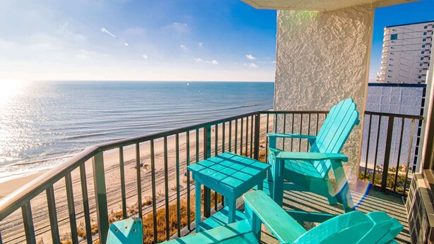 Un balcone con vista sull'oceano, con due sedie e un tavolino.