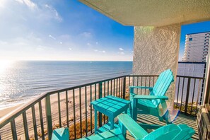Un balcon avec vue sur l’océan, comprenant deux chaises et une petite table.