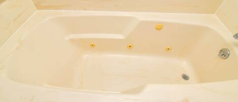Une grande baignoire vide, avec un robinet et trois vannes jaunes.