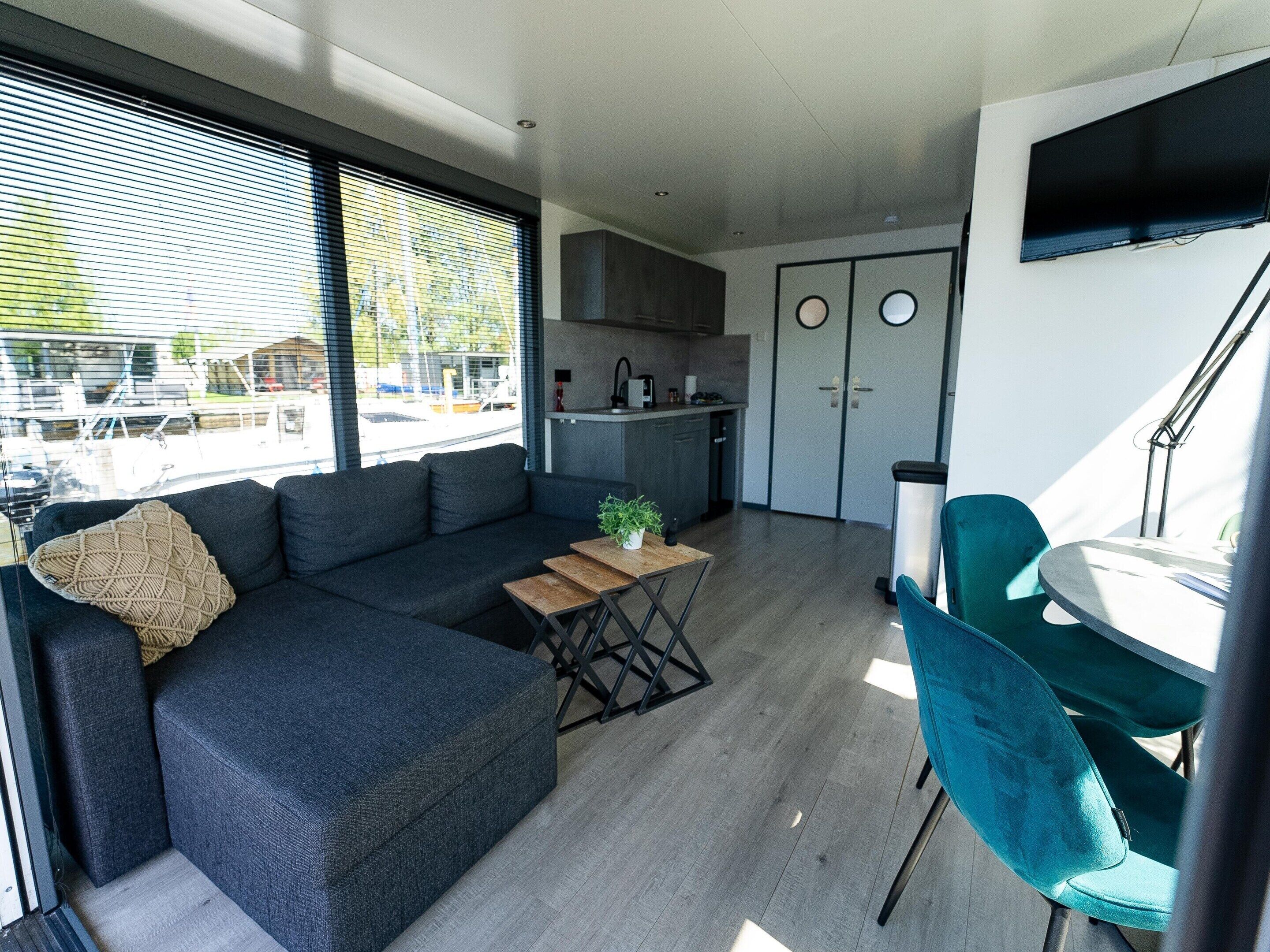 A modern living room with a dark blue sofa, a wooden coffee table, and a teal chair.