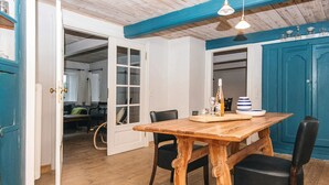 Uma mesa de jantar de madeira com cadeiras em um quarto com paredes azuis e piso de madeira.