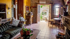 Un salon confortable avec un canapé, une table basse agrémentée de fleurs, un coin repas avec une table et des chaises, et une cuisine équipée d’une cuisinière et de placards.