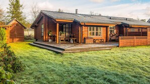 A log cabin with a deck, a covered patio, and a small shed in a grassy yard. - 4 Star Holiday Home in Farvang (Farvang)