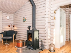 A log cabin interior with a wood-burning stove, a chair, a clock, and a door. - 4 Star Holiday Home in Farvang (Farvang)