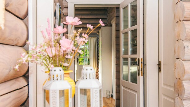 A wooden table with two white lanterns and a vase of pink flowers. - 4 Star Holiday Home in Farvang (Farvang)