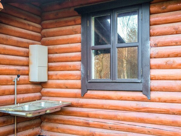 A log cabin with a window, a metal sink, and a wall-mounted electrical box. - 4 Star Holiday Home in Farvang (Farvang)