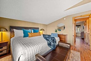 Un dormitorio con una cama grande, mesitas de noche, un espejo y vistas hacia otra habitación.