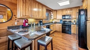 Eine Küche mit Holzschränken, einer Granit-Arbeitsplatte, einem schwarzen Kühlschrank und einer eingebauten Mikrowelle.