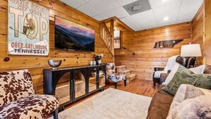 A cozy cabin interior with a wooden interior, a large painting of a landscape, and a sign that reads 'SEE YOU AT THE TOP OBER-GATLINBURG TENNESSEE'. - Stunning Views at Chateau LeConte • Hot Tub (Gatlinburg)