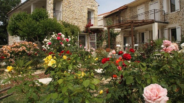 Un bâtiment en pierre doté d’un balcon et d’un jardin où poussent différentes sortes de fleurs.