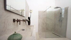 Une salle de bain moderne avec une douche à parois de verre, un comptoir en marbre et un vase vert.