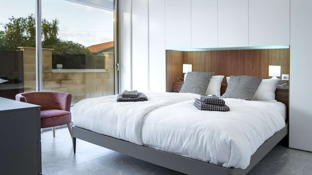 A modern bedroom with a large bed, a desk, and a chair.