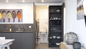 A modern kitchen with grey cabinets, a white sink, and a built-in wine fridge.