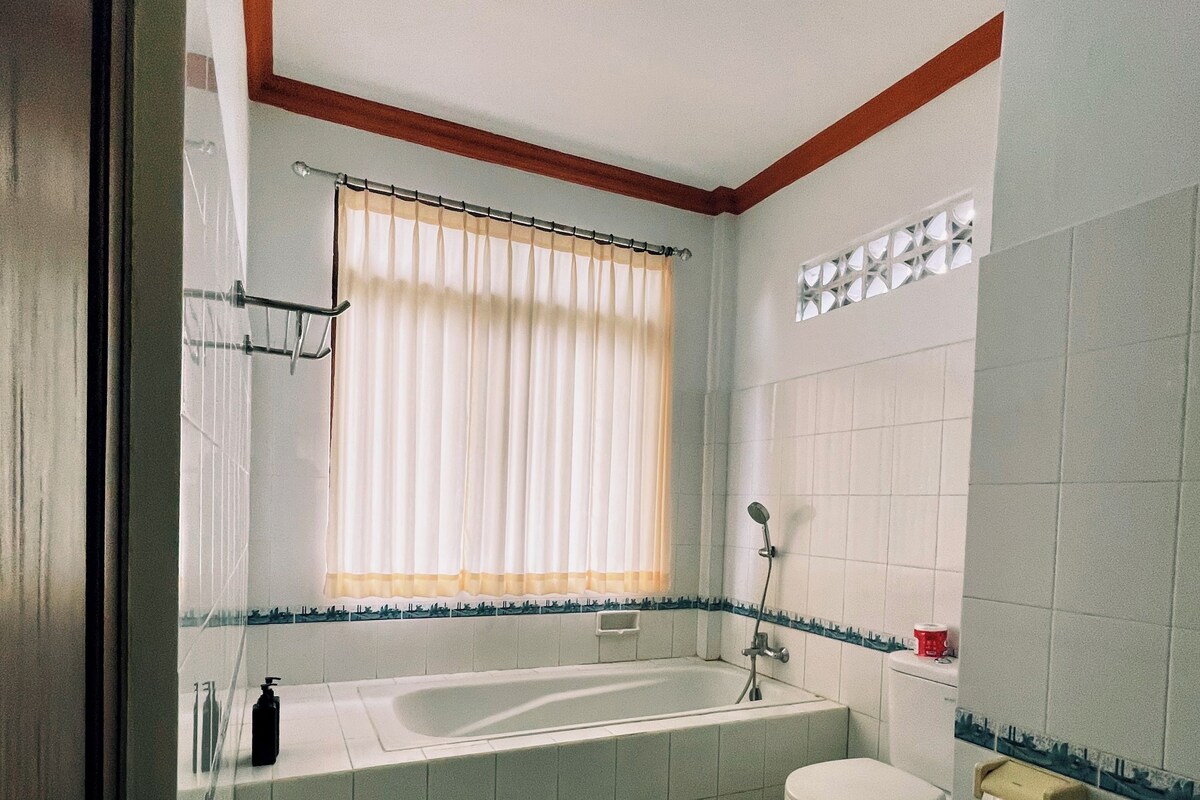Ein Badezimmer mit Badewanne, Toilette und einem fenster mit Vorhängen.