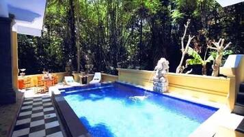 Een buitenzwembad, ligstoelen bij het zwembad