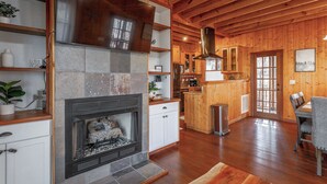Una cocina rústica con chimenea de piedra, armarios de madera y techo de madera.