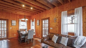 Un interior de madera con una zona de comedor, un sofá y una cruz en la pared.