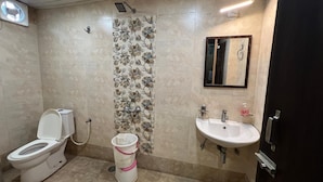 Een badkamer met toilet, wastafel, spiegel en douche.