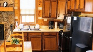 A kitchen with wooden cabinets, a sink, a stove, and a refrigerator.