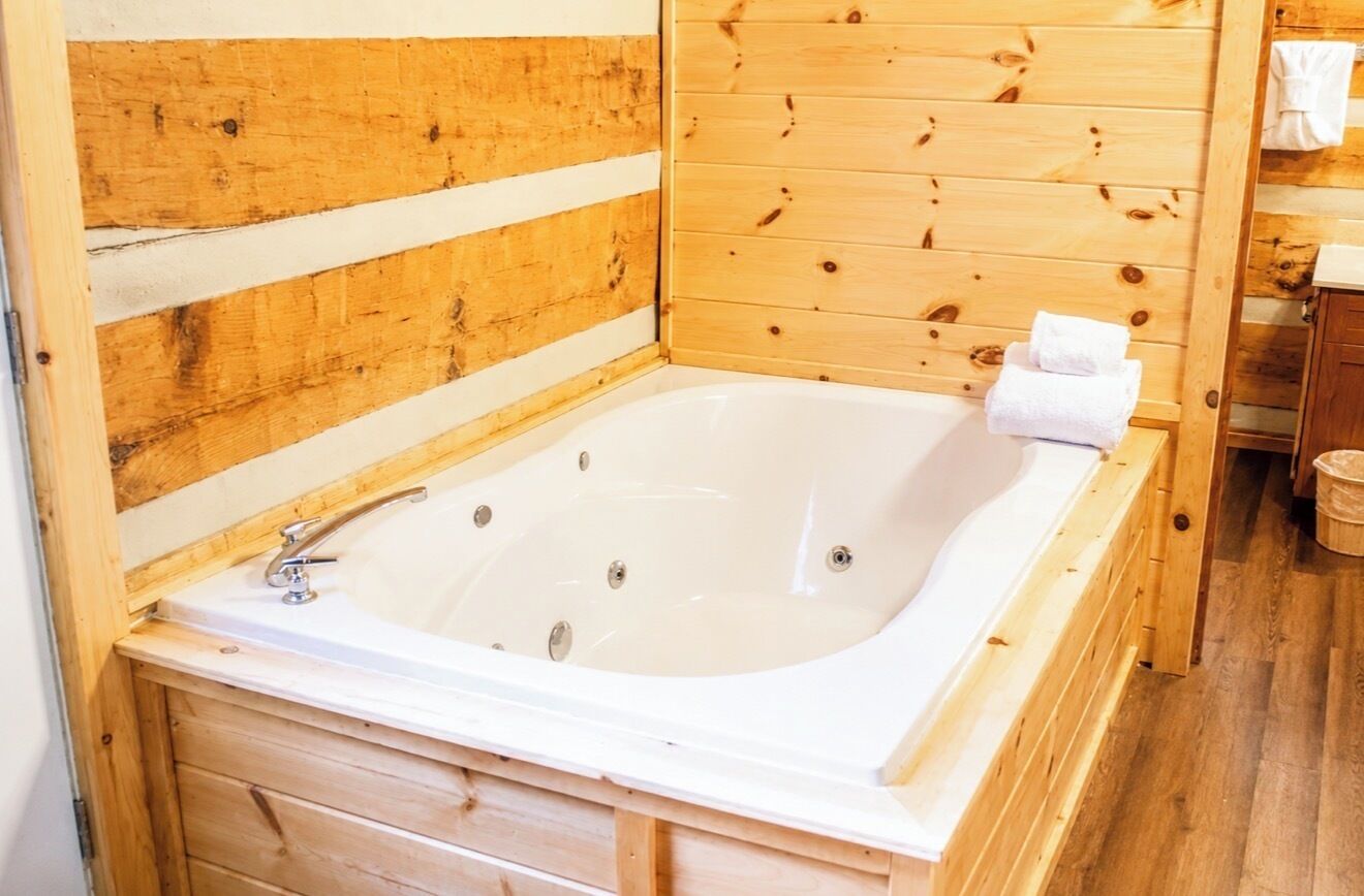 A wooden cabin with a wooden bathtub, wooden walls, and a wooden floor.