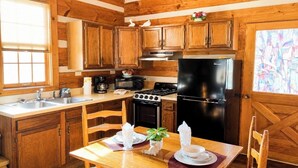 Una cocina tipo cabaña de madera con estufa, refrigerador y armarios de madera.