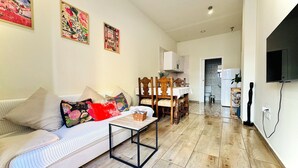 A living room with a sofa, coffee table, and a dining area with a table and chairs. - A DIFFERENT SPACE IN TRIANA (Sevilla)