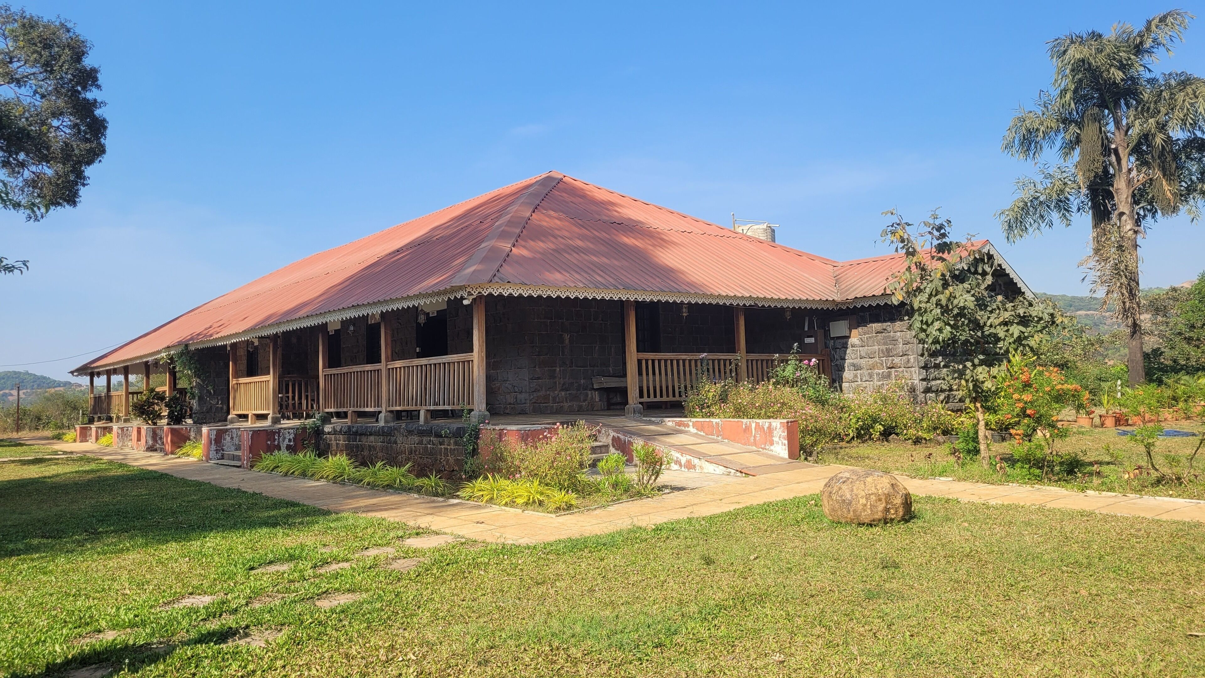 Ein rustikales Steinhaus mit rotem Metalldach, einer Holzveranda und Steinmauern.