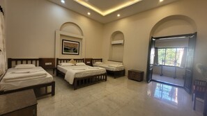 A hotel room with four beds, a painting on the wall, an air conditioning unit, and a balcony with a view. - Madhuvan Retreat Resort Amba (Shahuwadi)