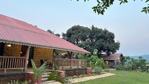 Een rustieke lodge met een gevel van natuursteen, een dak van rood metaal en een houten veranda.