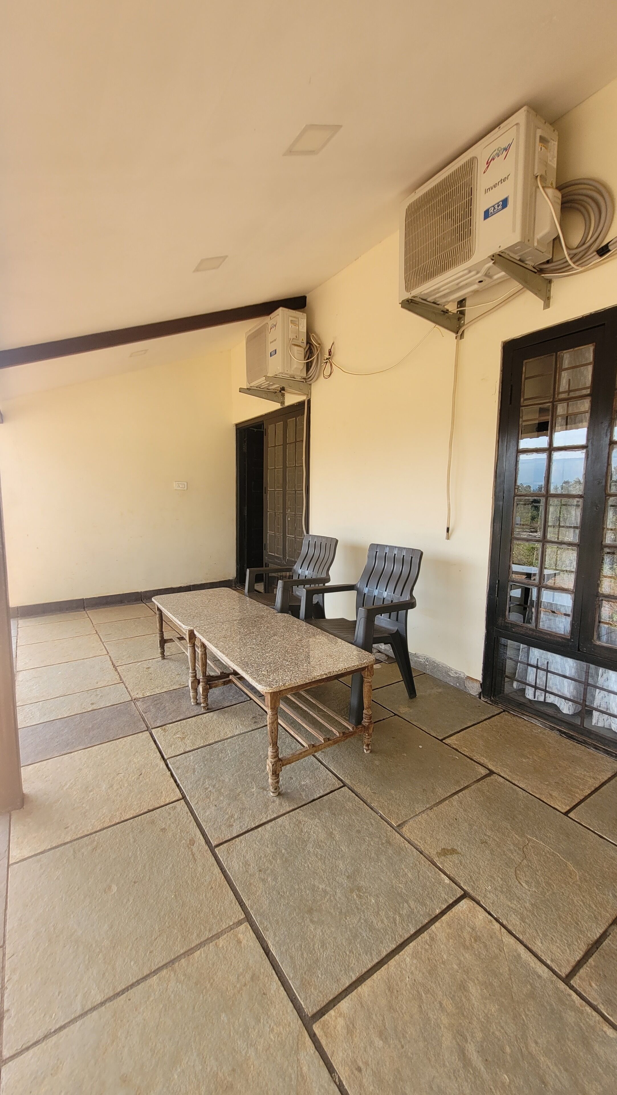 A conference room with a long table and four chairs, air conditioning units mounted on the wall, and a window with a view.