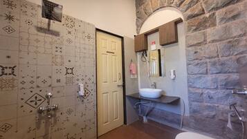A bathroom with a stone wall, a white sink, and a door with patterned tiles.