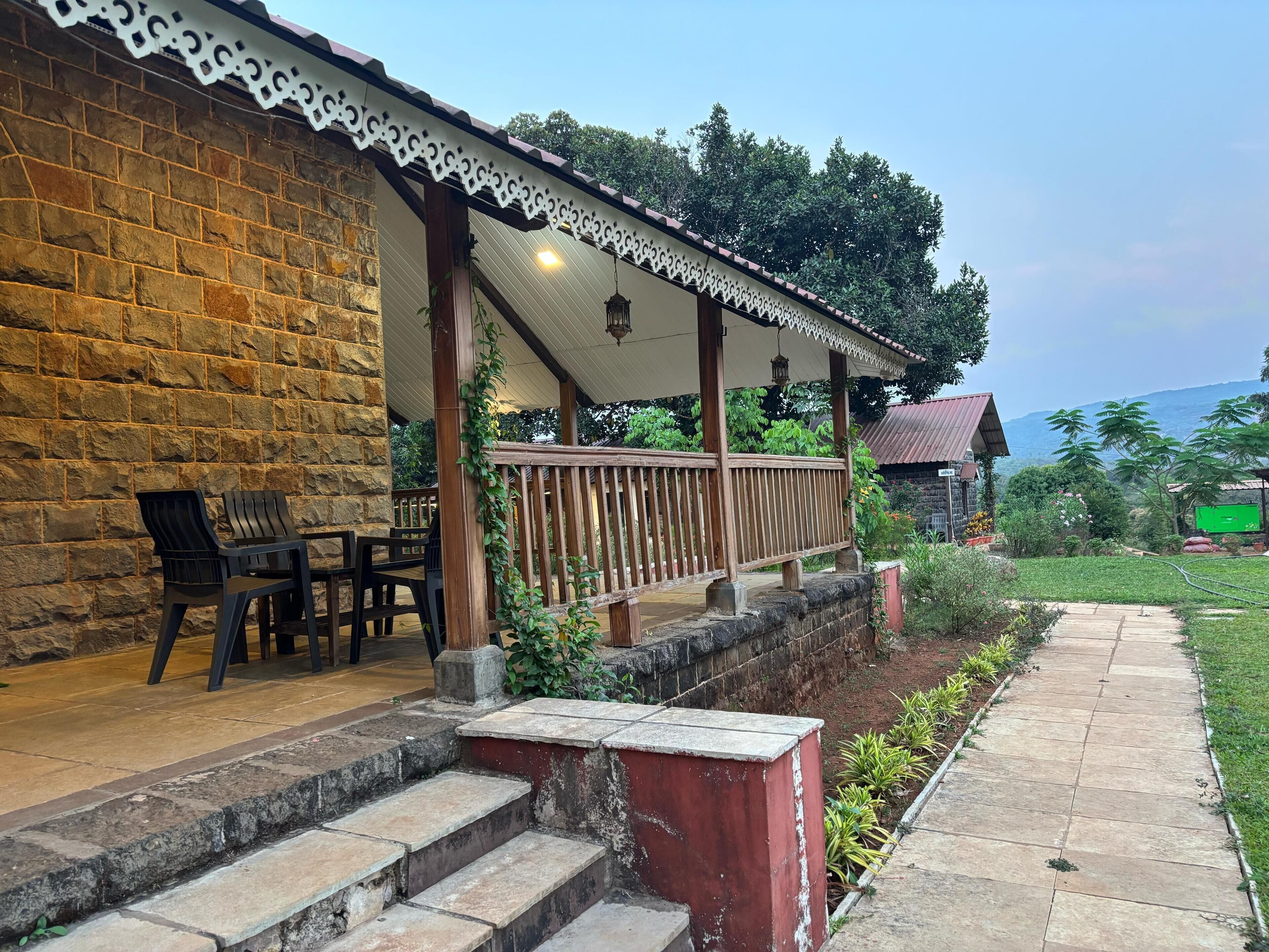 A stone building with a covered patio, outdoor seating, and a view of the surrounding landscape.