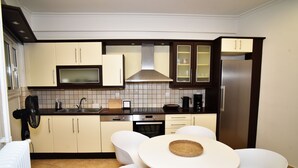 A compact kitchen with a microwave, stove, and sink. There is a dining table with chairs and a small island with a basket. - Acropolis Ifigenia Sunny 2 BR, Koukaki, Steps from Landmarks (Athina)