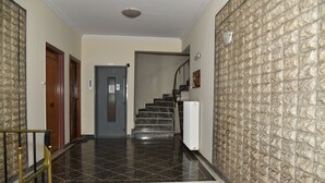 A hallway with a marble staircase, a door with a sign, and a textured wall. - Acropolis Ifigenia Sunny 2 BR, Koukaki, Steps from Landmarks (Athina)
